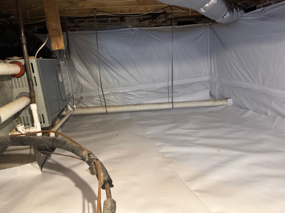 Cleansed crawl space with white vapor barrier and HVAC system, promoting moisture control.