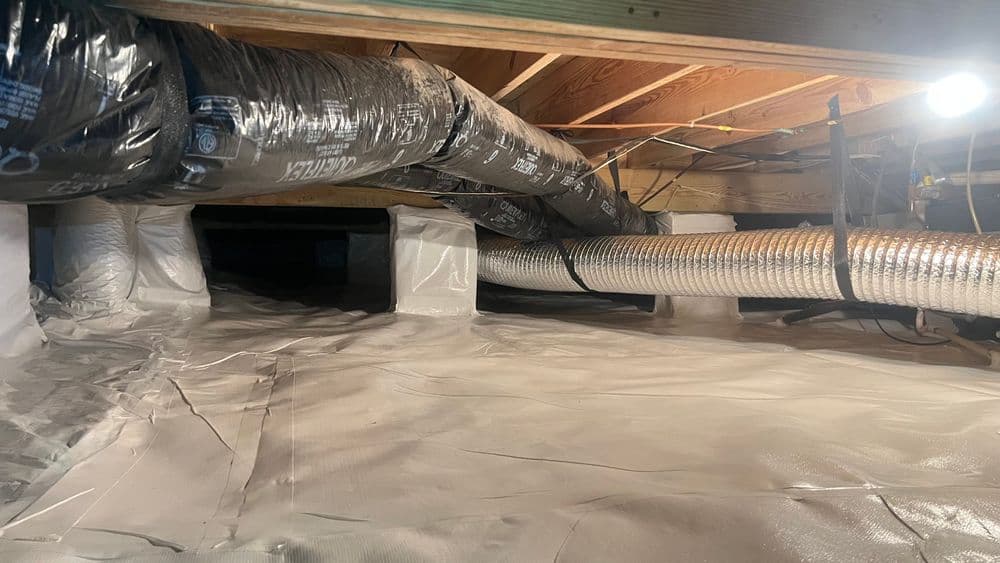 Insulated crawl space with ductwork and vapor barrier for energy efficiency and moisture control.