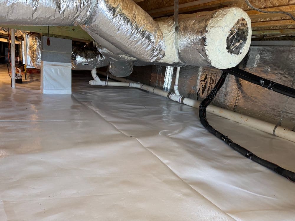 Clean, insulated crawl space with silver ductwork and white vapor barrier for moisture control.